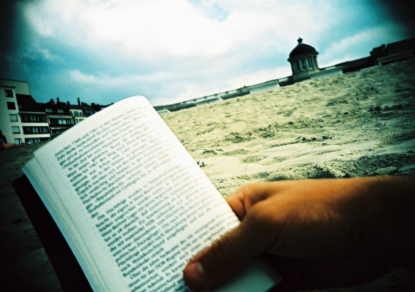 Hand mit Buch am Strand, Belgien